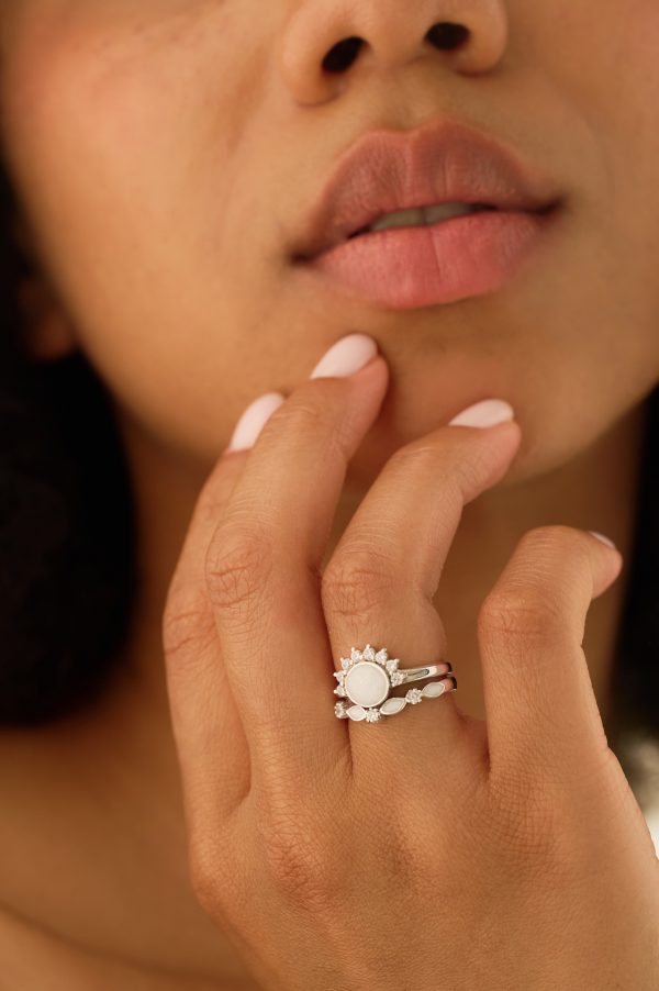 Close-up of a model’s hand wearing the Luna Sparkle breastmilk ring with round breast milk stone and cubic zirconia accents, stacked with the Serenity Sparkle Breastmilk Wishbone Ring.